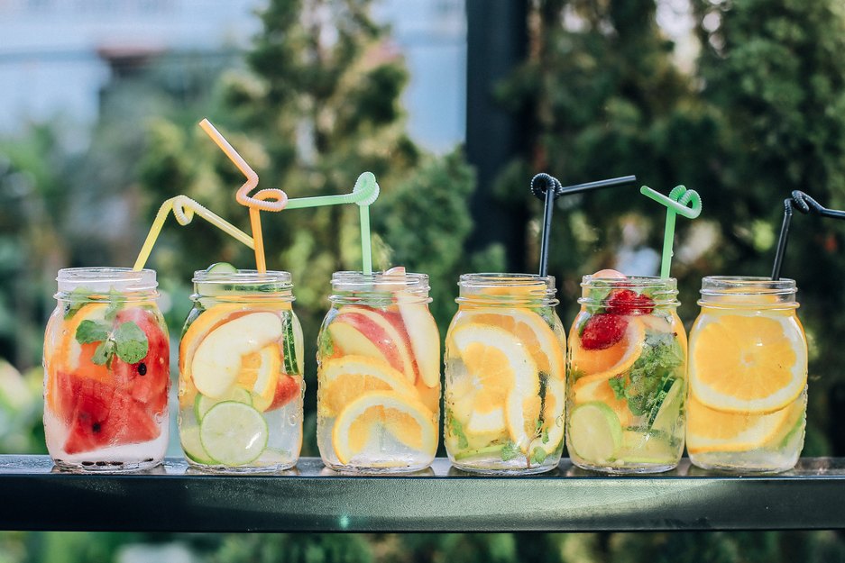 six fruity waters with sliced fruit and straws on table